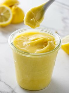 a spoon full of lemon custard on top of a jar