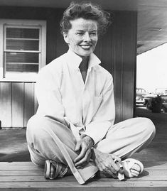 black and white photograph of a woman sitting on the porch with her feet propped up