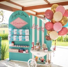 a display with balloons and desserts on the table in front of a blue striped wall