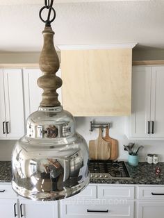 a kitchen with white cabinets and stainless steel pendant light hanging from the ceiling over the stove