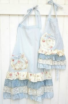 two aprons are hanging on a white fence with blue and white striped fabric,