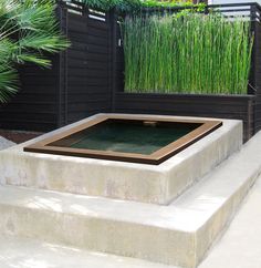 an outdoor water feature in the middle of a concrete step with grass growing behind it