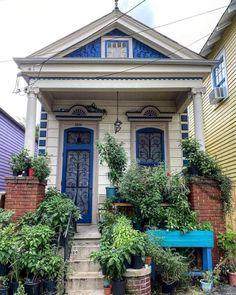 a house with potted plants in front of it and stairs leading up to the door