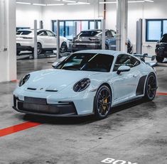 a white porsche parked in a garage next to other cars