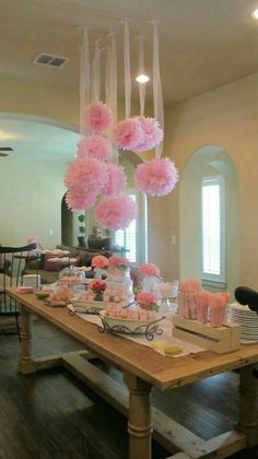 a dining room table with pink flowers hanging from it's ceiling and plates on the table