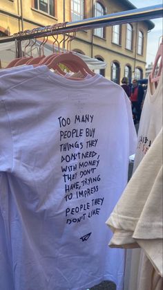 t - shirts with words written on them hanging from clothes racks in front of buildings