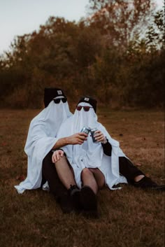 two people dressed in black and white sitting on the ground with their heads wrapped around each other