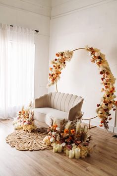 a couch sitting on top of a hard wood floor next to a white chair and flowers