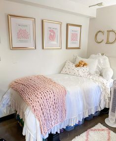 a white bed sitting next to a window with pictures on the wall and a teddy bear laying on top of it