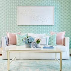 a living room filled with furniture and flowers on top of a coffee table in front of a painting