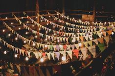 many people are sitting in a large room with flags strung from the ceiling and candles lit up