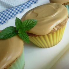 two cupcakes with frosting and a green leaf on top are sitting on a plate