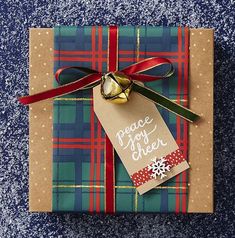 a present wrapped in plaid paper with a red ribbon and a tag that says peace not cheer