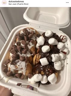 a plastic container filled with marshmallows, chocolate and other toppings on top