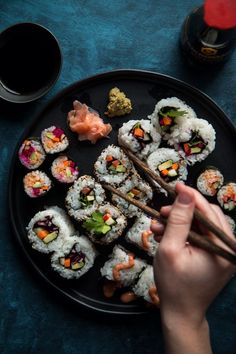 sushi on a black plate with chopsticks