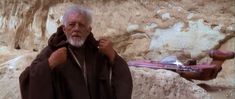 an old man sitting on top of a large rock next to a guitar in the background