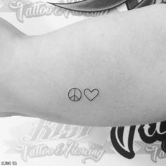 two hearts and a peace sign tattoo on the left inner arm, which is black and white