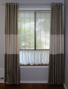 the curtains are hanging in front of the window with white and brown drapes on it