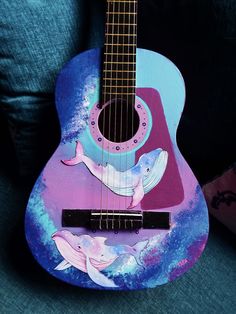 a painted guitar sitting on top of a blue couch