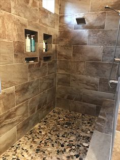 a walk in shower sitting next to a tiled wall and floor with rocks on the ground