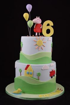 a three tiered cake with pep the pig on top and balloons in the air