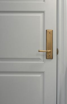 an open door with a gold handle on it's side and the bottom part of the door painted white