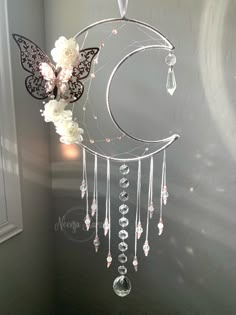 a wind chime hanging from the side of a wall with flowers and butterflies on it