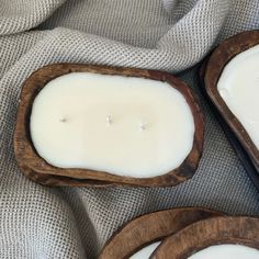 two wooden trays filled with white candles on top of a gray cloth covered table