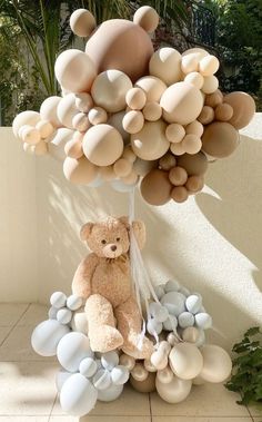 a teddy bear sitting on top of a bunch of balloons in the shape of trees