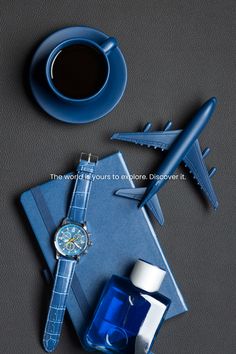 an airplane, watch, and cup of coffee are arranged on a table next to each other