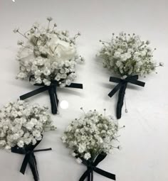 four bouquets of white flowers with black ribbons