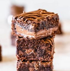 three chocolate brownies stacked on top of each other with one piece cut in half