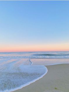 the ocean waves are rolling in and out of the water at sunset on a sandy beach