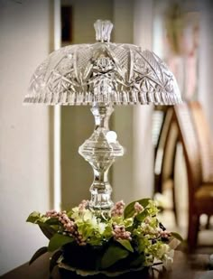 a glass lamp sitting on top of a table next to a vase filled with flowers