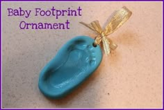 a baby footprint ornament with a gold bow on it's back