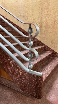 a metal hand rail on top of a set of stairs next to a carpeted floor