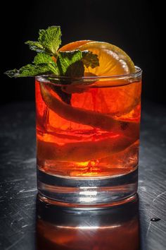 a close up of a drink in a glass with ice and mint on the rim