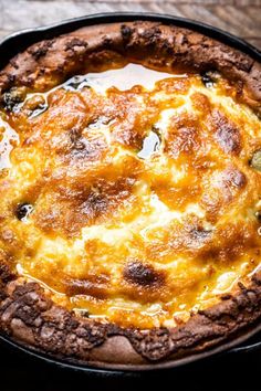 a baked dish with cheese and sauce in a black pan on a wooden table top