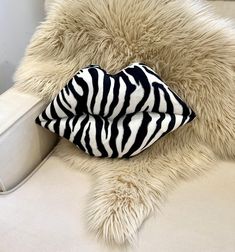 a zebra print pillow sitting on top of a white couch next to a furry rug