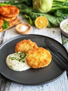 two crab cakes on a black plate with cream sauce