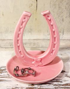 a pink ceramic ring holder with handcuffs on it