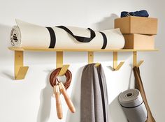 a wall mounted shelf with various items on it and hanging from the top, along with two pairs of yoga mats