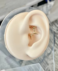 an ear with a gold star on it sitting in a display case at a jewelry store