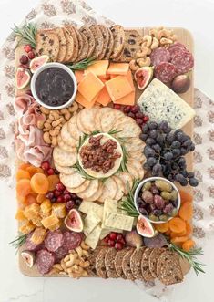 an assortment of cheeses, crackers and meats on a platter