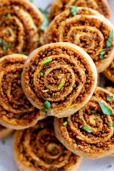 there are many rolls on the plate with green garnishes around them and sprinkled with parsley