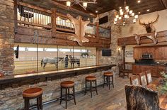 a rustic bar with wooden stools and deer heads on the wall