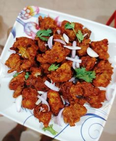 a white plate topped with fried food and garnished in cilantro sauce