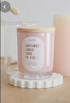 a pink candle sitting on top of a wooden table next to a glass container with a straw sticking out of it