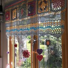 a kitchen window covered in lots of colorful crocheted decorations and hearts hanging from the windowsill