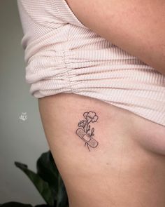 a woman's stomach with a small flower tattoo on the left side of her abdomen